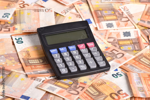 the calculator lays on the money.Euros are scattered on the table. © Alexandr