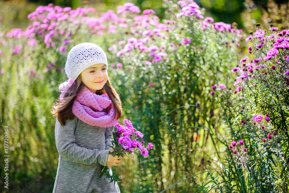happy little girl is walking in a beautiful park with a bouquet of flowers. happy little girl is walking in a beautiful park with a bouquet of flowers.