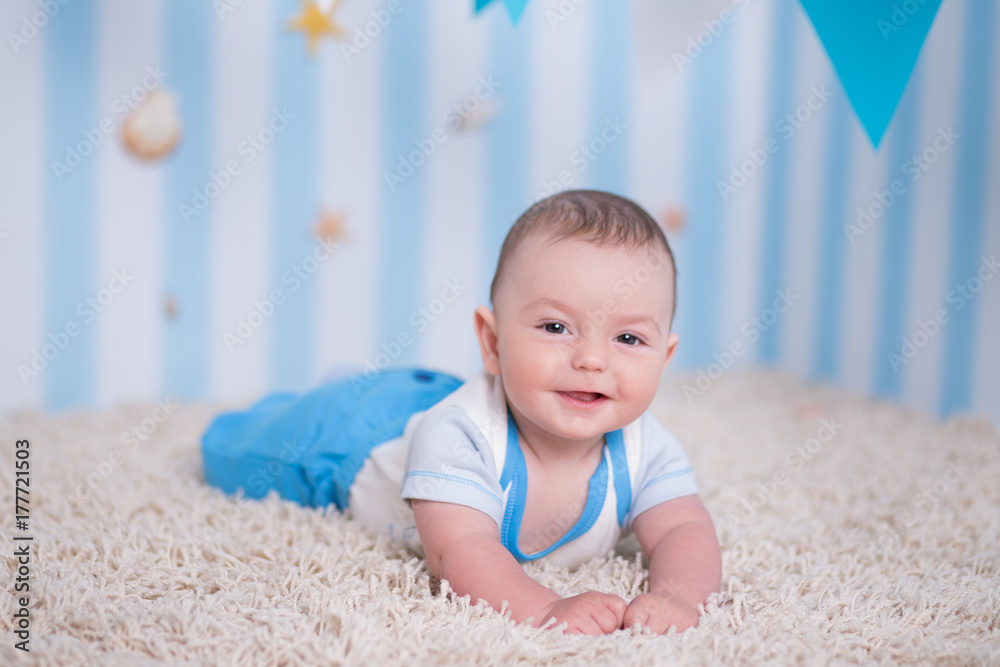 Handsome funny happy baby child boy posing on fur wooden table in blue studio Handsome funny happy baby child boy posing on fur wooden table in blue studio