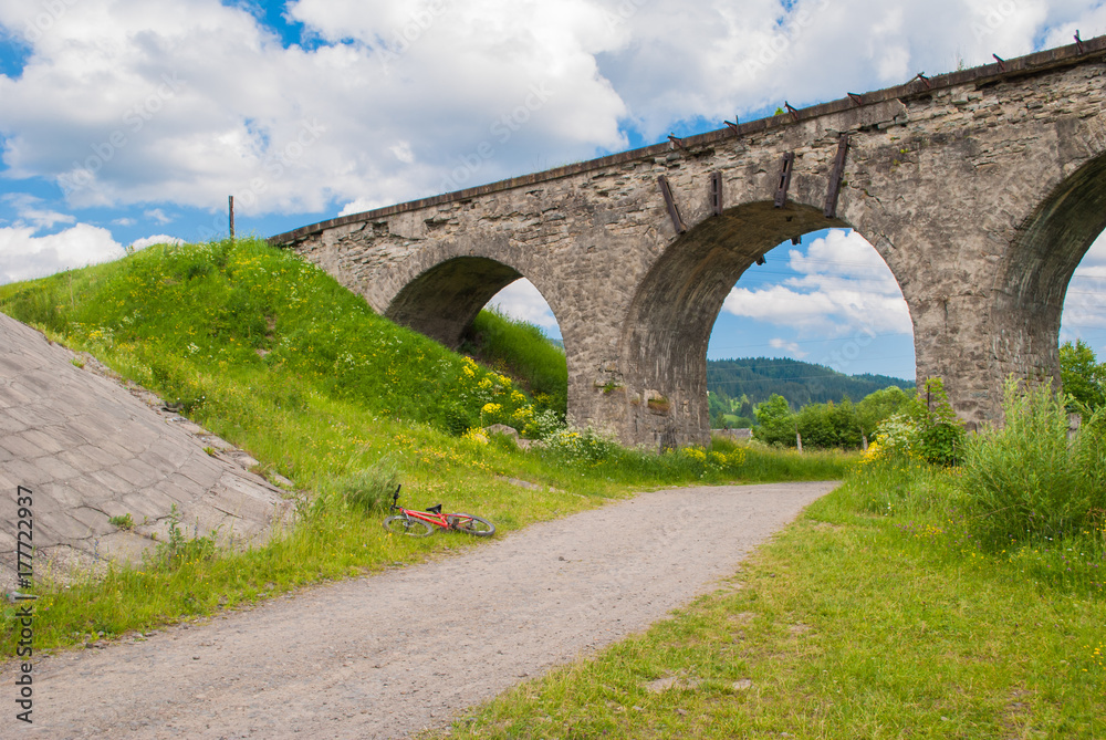 The old Austrian stone railway bridge viaduct in Vorokhta and bicycle near it