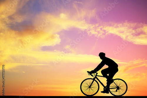 Silhouette man and bike relaxing on blurry sunrise background