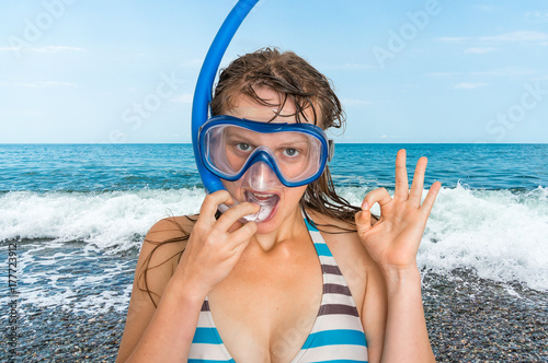 Woman with snorkeling mask for diving stands near the sea