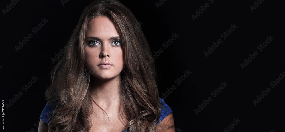 Beautiful woman in a blue dress posing on a black background Beautiful woman in a blue dress posing on a black background