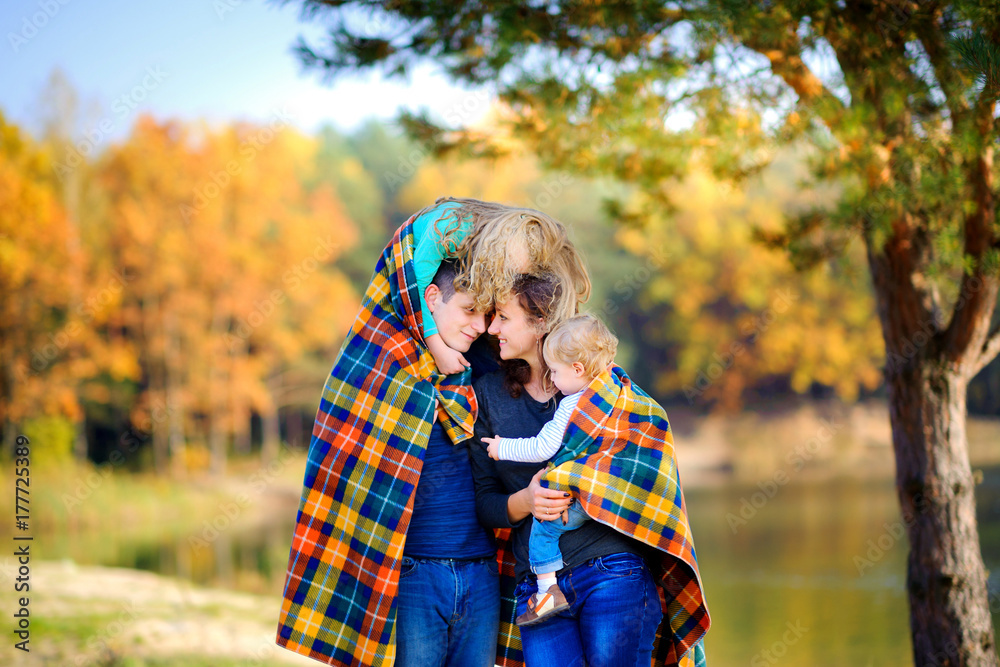 happy family walks in a beautiful autumn park, hugs and shelter a rug. happy family walks in a beautiful autumn park, hugs and shelter a rug.