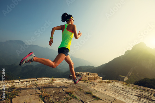Photography young woman trail runner running at great wall on the top of mountain