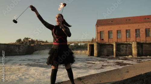 A young girl shows a fire show against the backdrop of an old German hydroelectric power station. photo