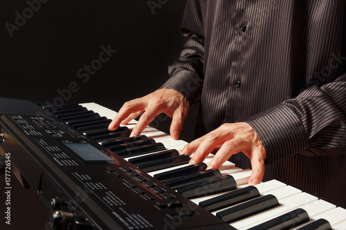 Musician play the keys of the digital piano on a black background