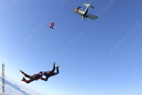 Skydivers are jumping out of a biplane.