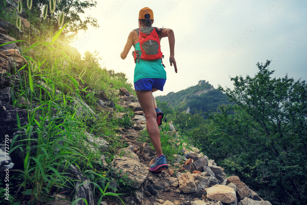 Obraz premium młoda kobieta biegacz szlak działa na wielką ścianę na szczycie góry