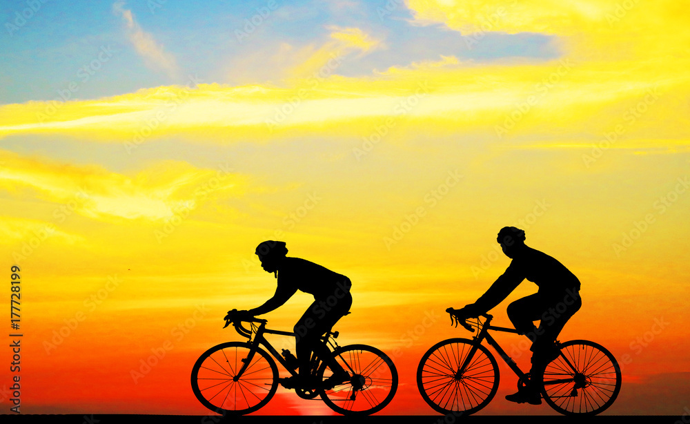 Obraz premium Silhouette man and bike relaxing on blurry sunrise background