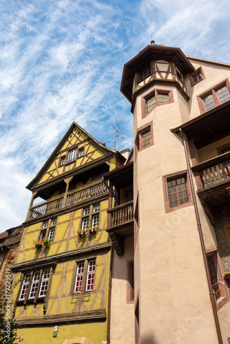 Fototapeta Naklejka Na Ścianę i Meble -  Altes Fachwerkhaus und ein Gebäude mit großem Turm in der schönen mittelalterlichen Stadt Colmar in Frankreich.
