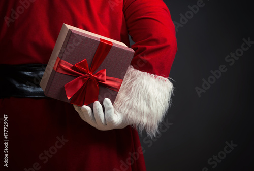 Santa Claus holding a presents, over a dark background