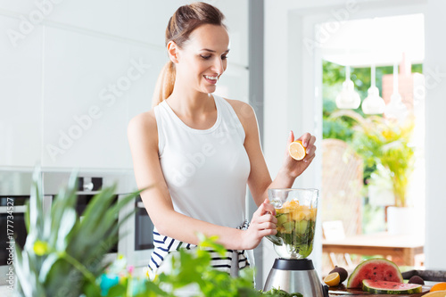Smiling girl squeezing fruit juice