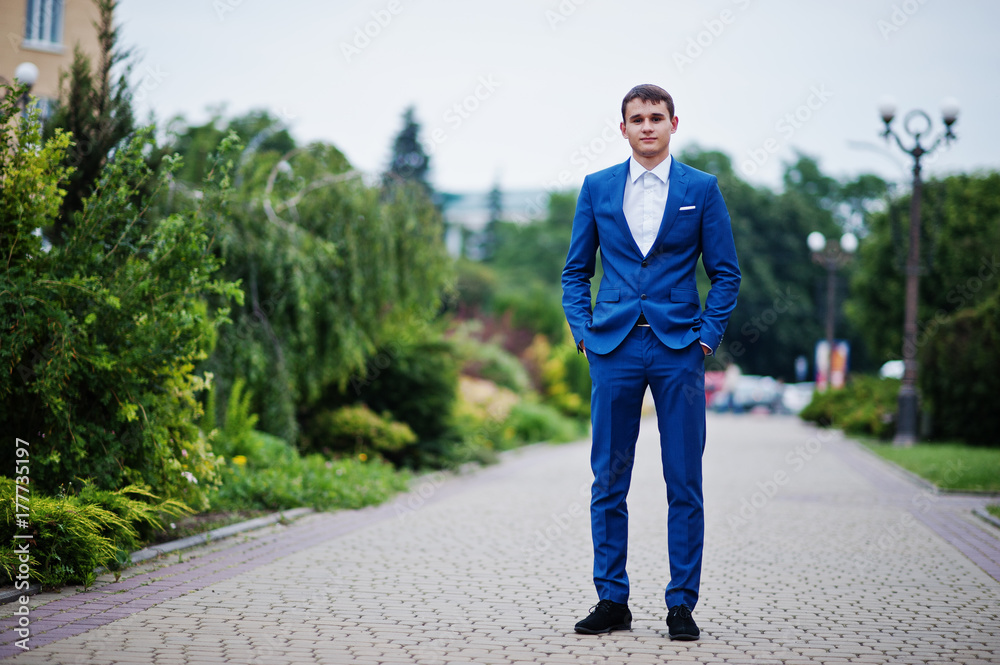 Portrait of a handsome young man in formal fancy suit posing on the pavement in the park on a prom day. Portrait of a handsome young man in formal fancy suit posing on the pavement in the park on a prom day.