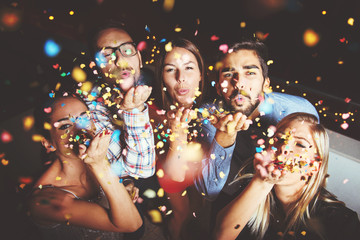 Group of people having a party, blowing confetti 