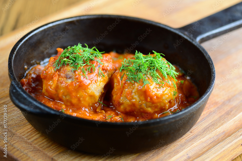 Meatballs in a thick tomato sauce in a frying pan. Beautiful serving of a delicious and hearty dinner. Closeup. Meatballs in a thick tomato sauce in a frying pan. Beautiful serving of a delicious and hearty dinner. Closeup.