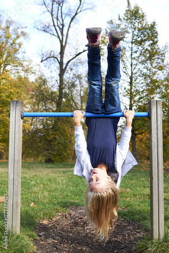 Child kid girl upside down on a park playground gym game