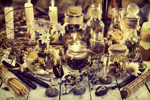 Healing herbs and berries, runes and candles on wooden table, toned image