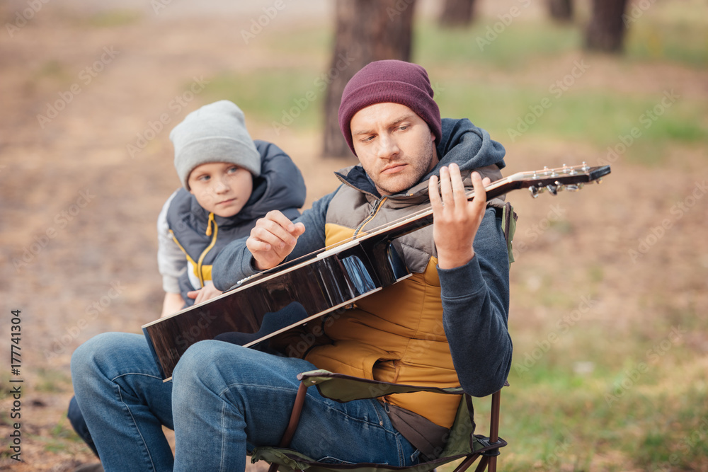father and son with guitar in forest