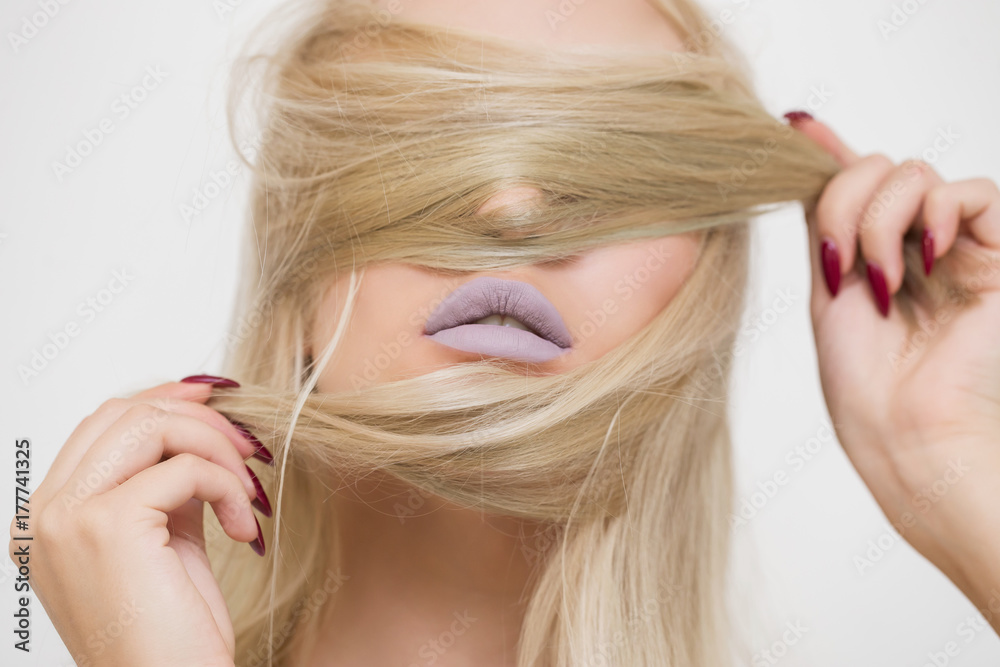 Fototapeta premium Beautiful blonde girl closes her eyes and chin hair. Is the lipstick, the hair. Makeup, cosmetics, skin care