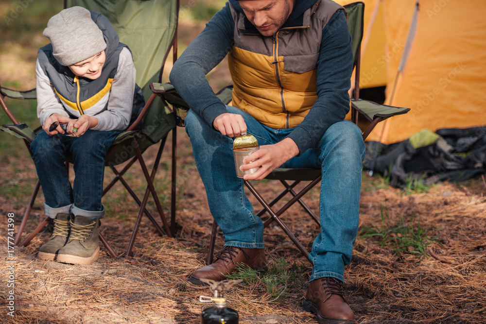 father and son eating in forest father and son eating in forest