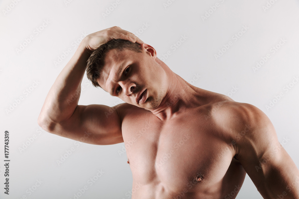 Handsome concentrated young sportsman stretching exercises