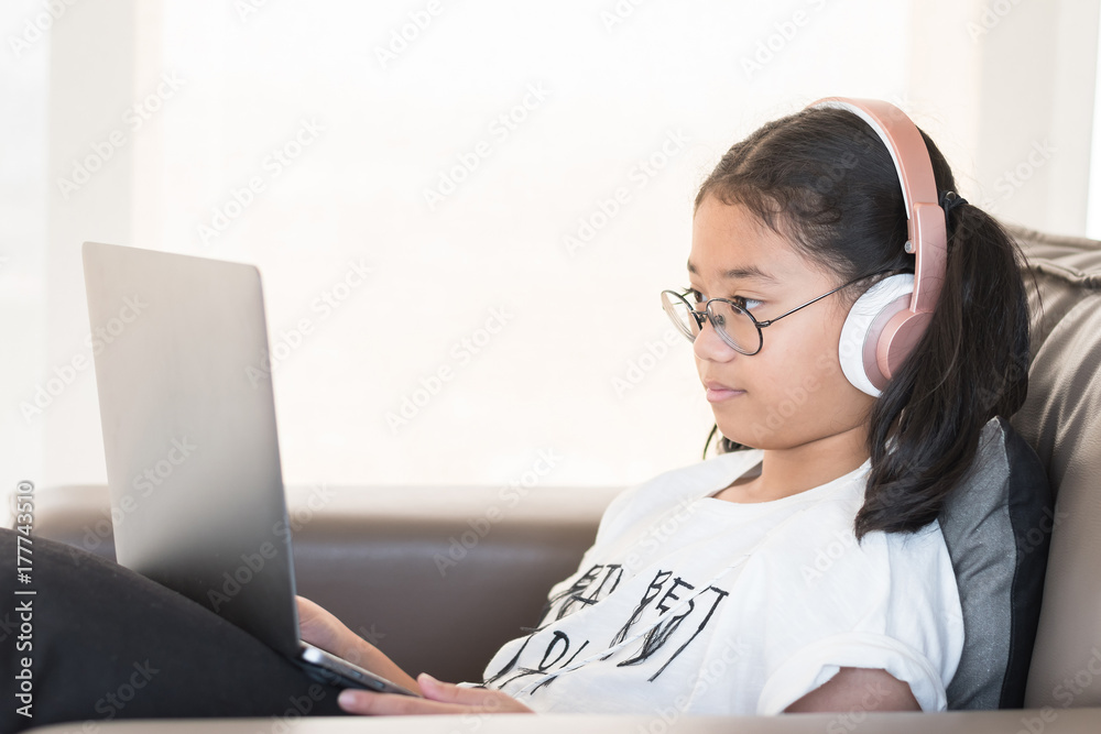 Digital technology education concept of school kid lifestyle with headphone using internet learning and reading e-book on mobile computer software for educational studying and playing online game Digital technology education concept of school kid lifestyle with headphone using internet learning and reading e-book on mobile computer software for educational studying and playing online game