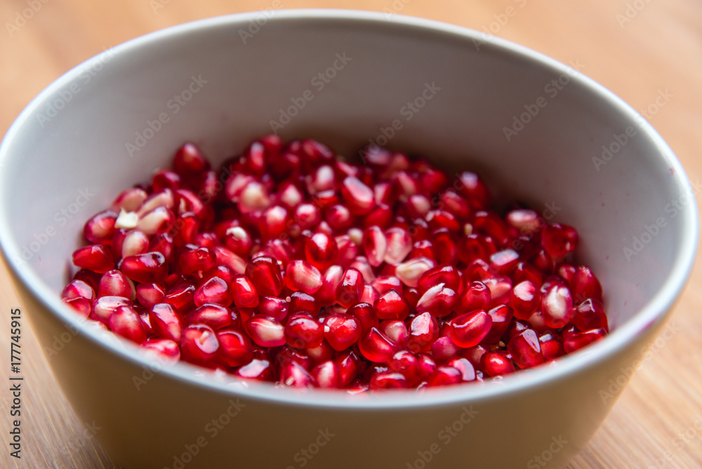 Grani melograno in una tazza su tavolo Grani melograno in una tazza su tavolo
