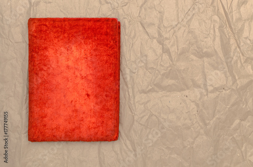 Closed vintage red book isolated on crumpled paper page surface background with copy space.