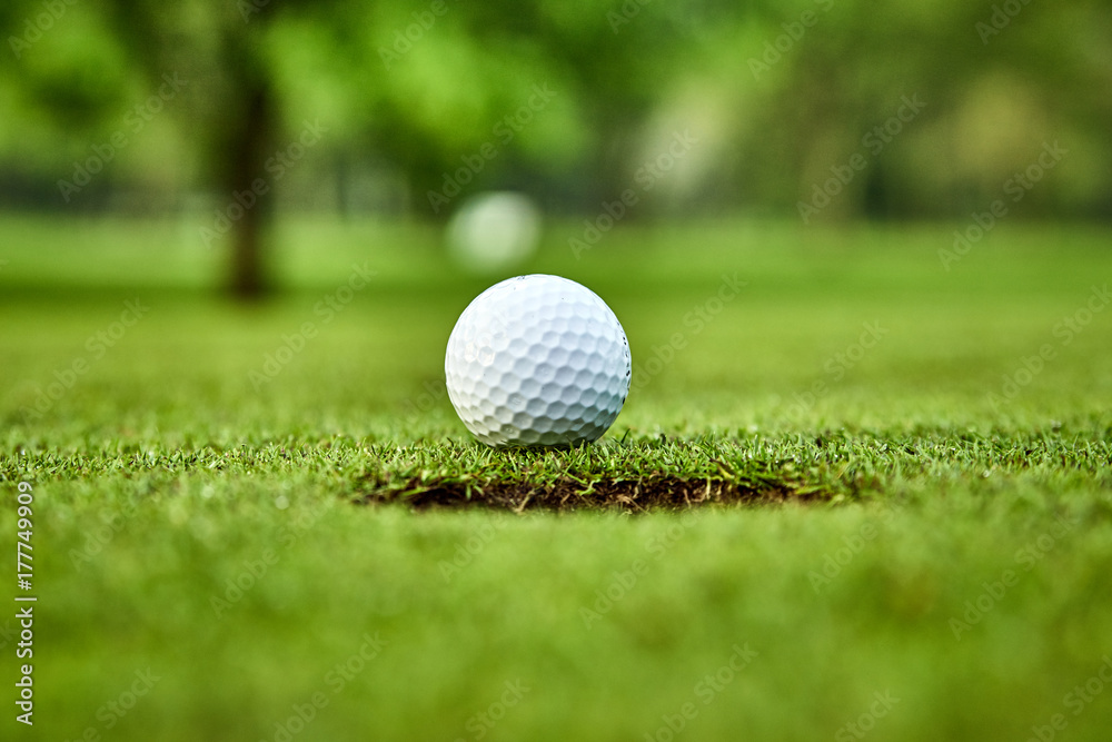 Golf ball on the green. golf ball on lip of cup Golf ball on the green. golf ball on lip of cup
