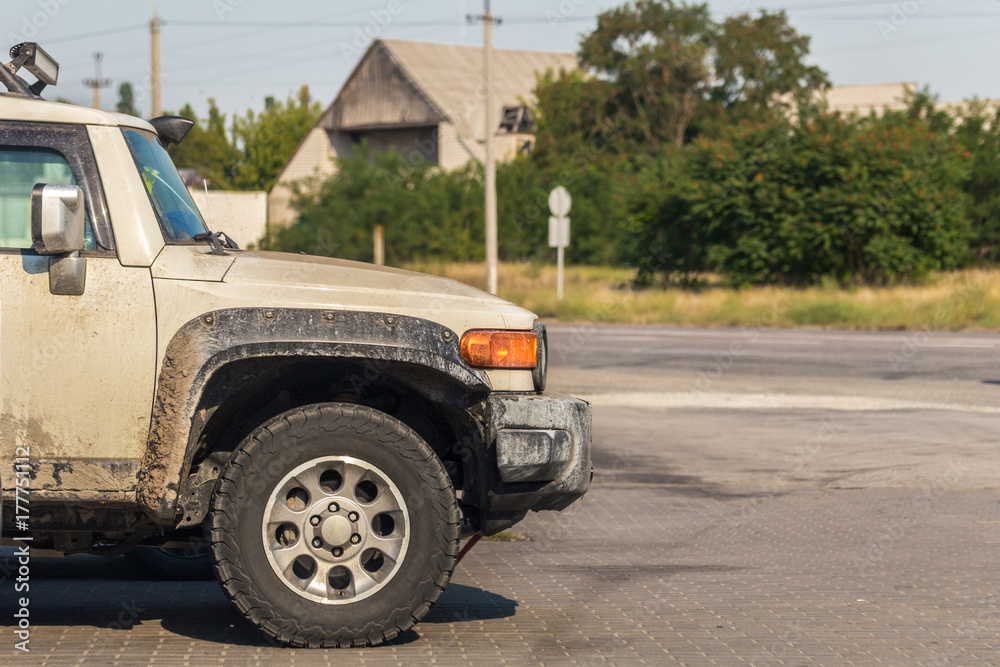 Side view of offroad car's wheel soiled in mud and dirt after trophy all-terrain competition in rural area Side view of offroad car's wheel soiled in mud and dirt after trophy all-terrain competition in rural area