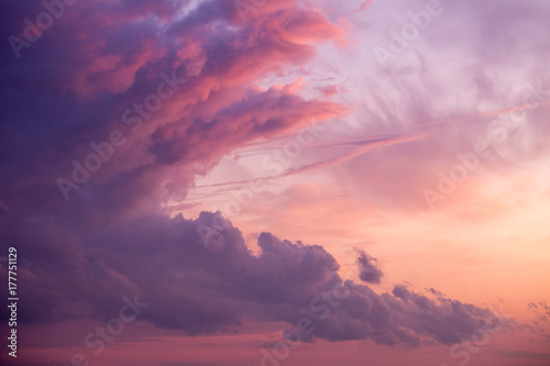 Dramatic and scenic cloudy sunset or sunrise  sky . Purple fiery lights. Wallpaper or background