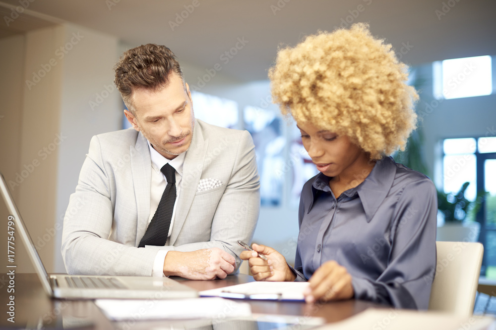 Businesswoman and businessman working on laptop