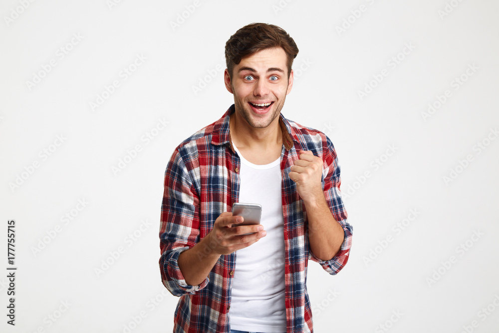 Portrait of a happy surprised man looking holding mobile phone Portrait of a happy surprised man looking holding mobile phone
