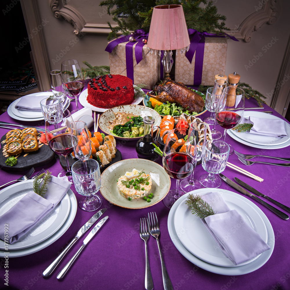 Christmas holiday table purple color with sushi, salad, meat and many delicious dishes with white plates beautiful Christmas holiday table purple color with sushi, salad, meat and many delicious dishes with white plates beautiful