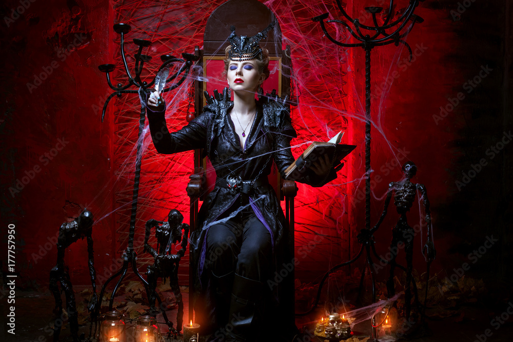 A female witch sits on a throne in a red room and conjures