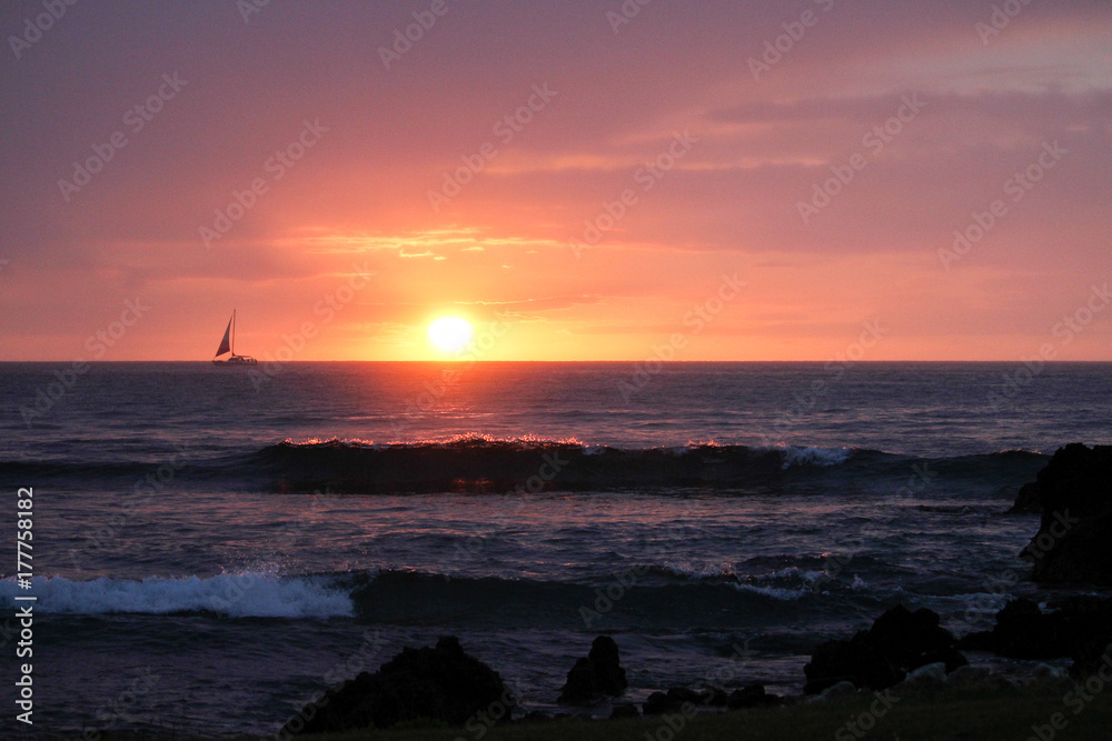 sailboat sailing across setting sun