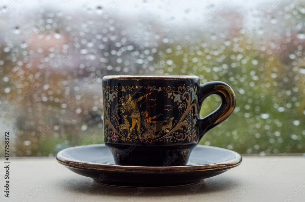 Fototapeta premium A cup of coffee on the window in the rain