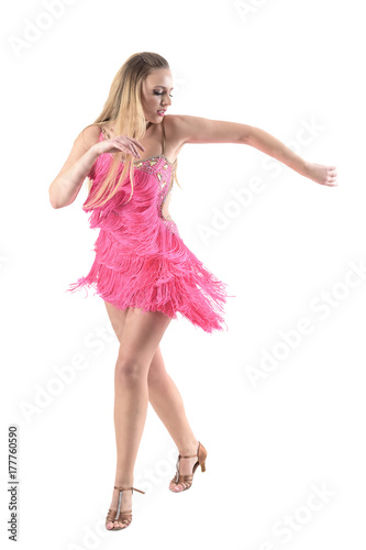 Gorgeous blonde female dancer dancing salsa in pink fringed dress looking down. Full body length portrait isolated on white studio background. 