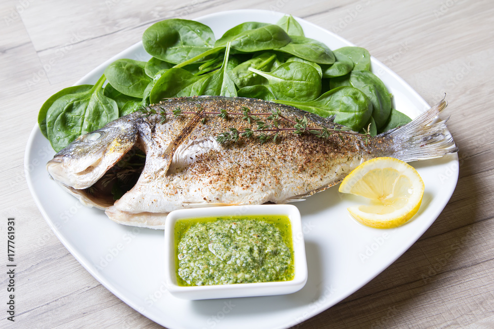 Baked Dorado with spinach and pesto sauce. Close-up. Selective focus. Baked Dorado with spinach and pesto sauce. Close-up. Selective focus.