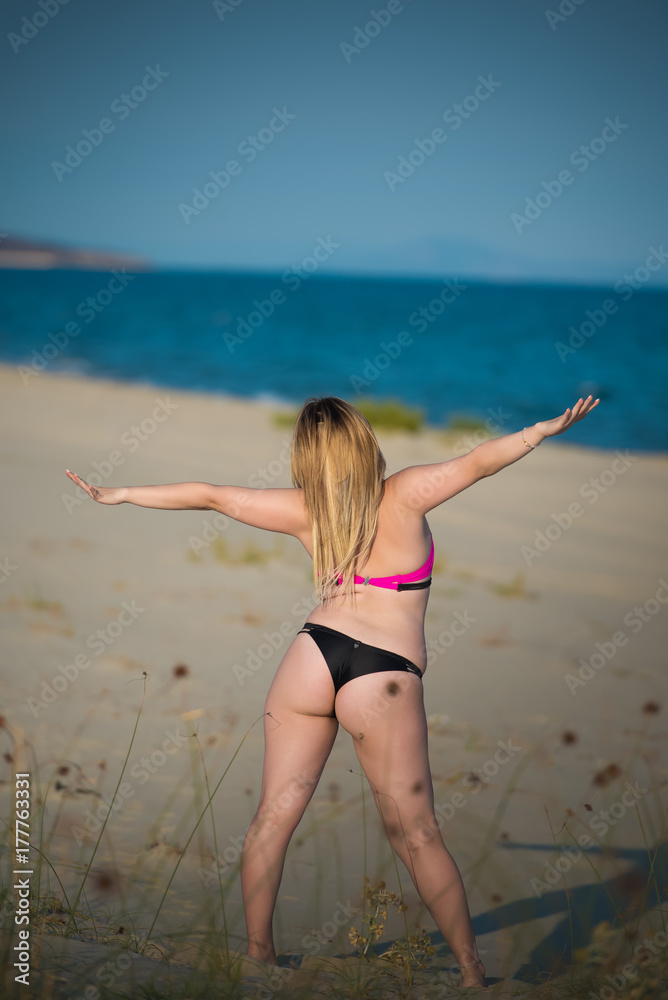 Young woman wear bikini and stretch her body as she enjoying the view of the sea Young woman wear bikini and stretch her body as she enjoying the view of the sea