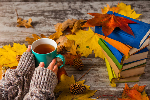 Autumn. Hands holding a Cup of tea. Books colorful.
