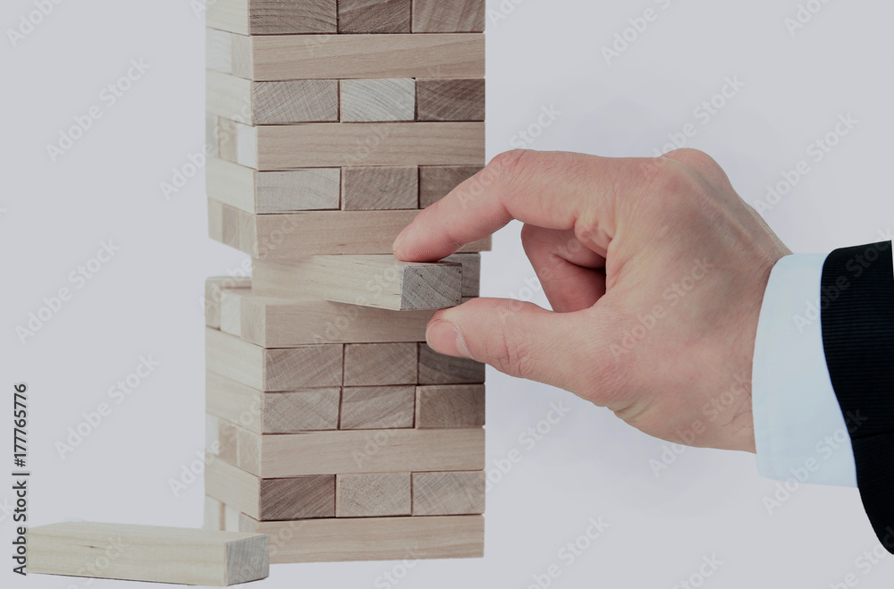 The tower from wooden blocks and man's hand take one block