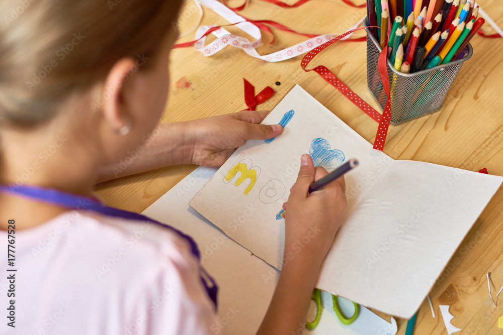 High angle portrait of teenage girl making gift card for mom on Mothers day during art and craft class in school High angle portrait of teenage girl making gift card for mom on Mothers day during art and craft class in school