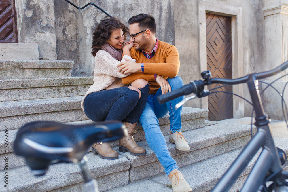 Obraz premium Young couple with bicycle siting on stairs in the city.