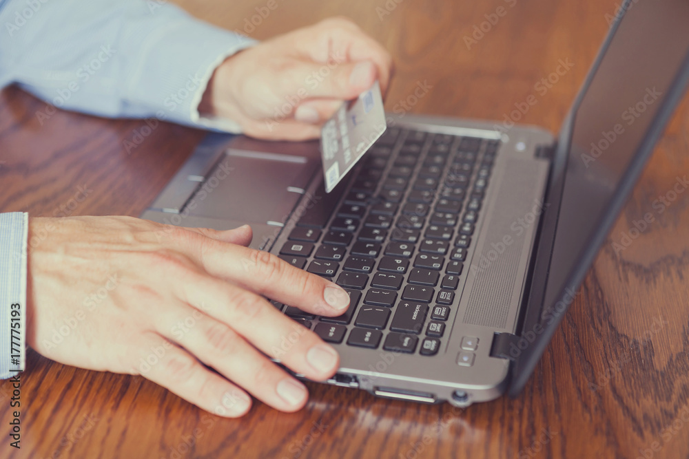Men's hands holding credit card and using laptop - online shopping Men's hands holding credit card and using laptop - online shopping