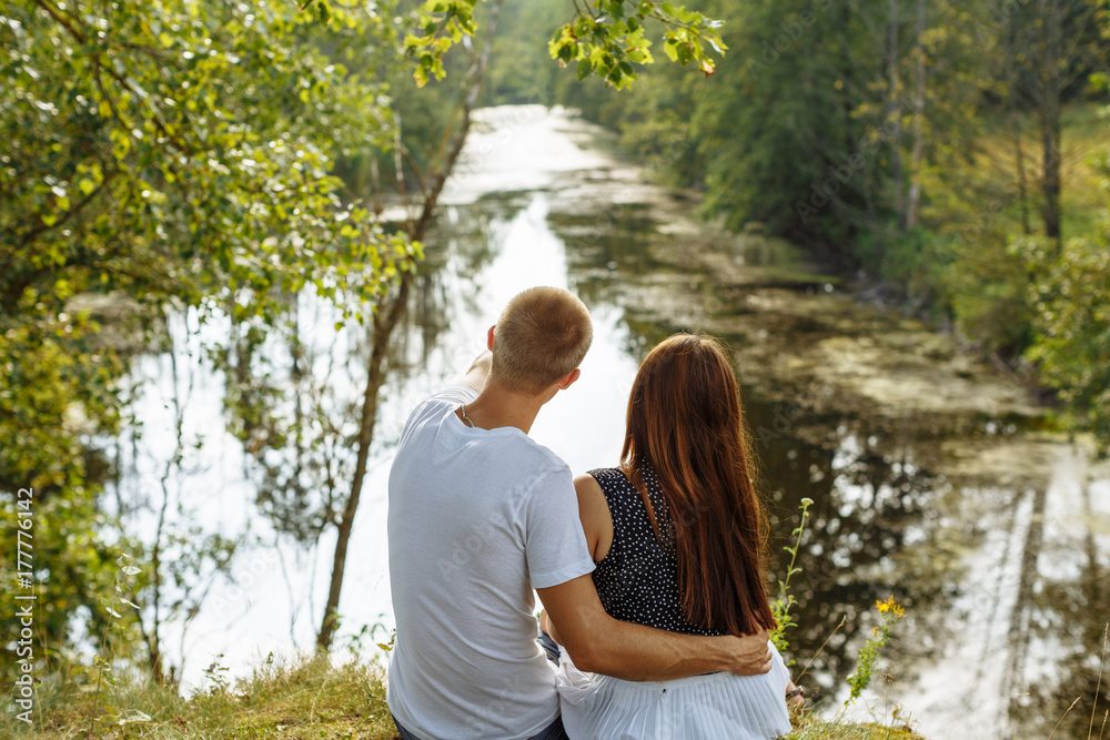 Парень и девушка сидят в обнимку у реки
