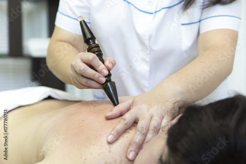 Masseur using sticks to massage female. Young doctor doing massage full woman on back with a wooden stick