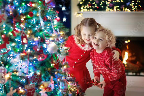 Children at Christmas tree. Kids at fireplace on Xmas eve