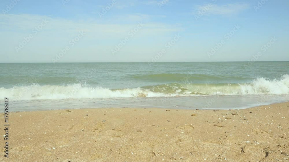A sandy beach with footprints and a little excitement on the water and a clear blue sky A sandy beach with footprints and a little excitement on the water and a clear blue sky
